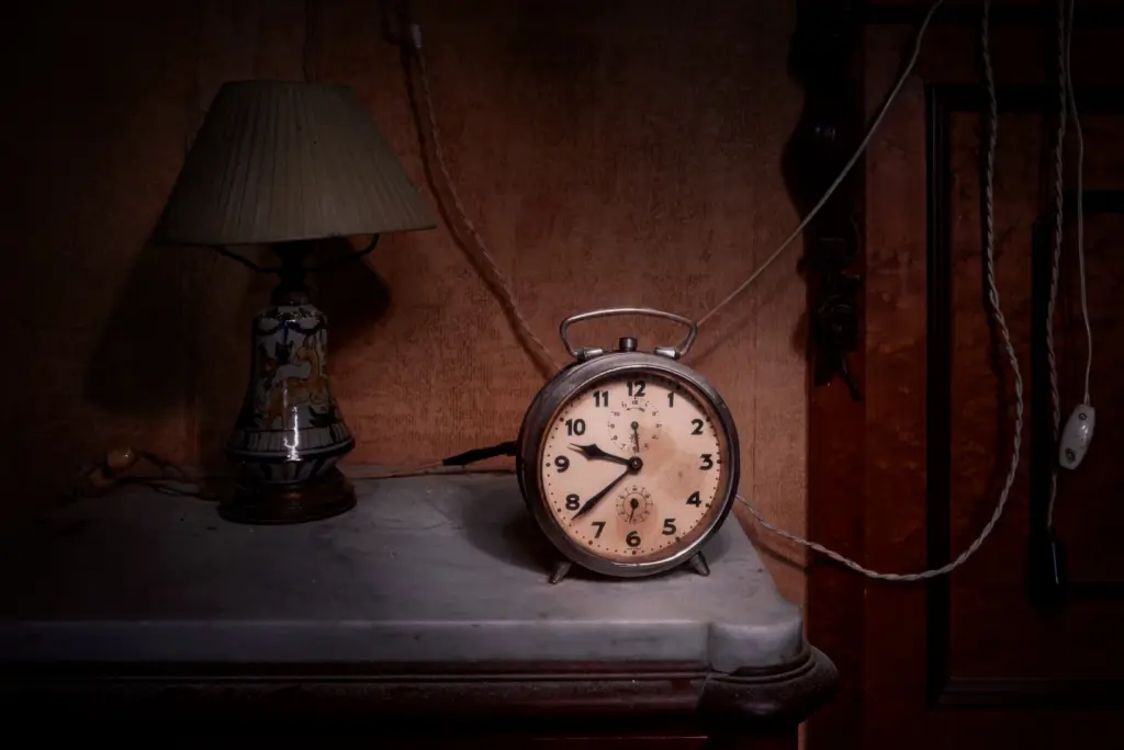 Sveglia vintage su un tavolo in una stanza abbandonata, con una lampada e fili elettrici